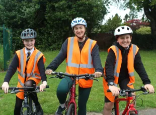 Instructor Olivia Batho-Samblas with two pupils from Forthill Primary School. They are sitting on bikes, all wearing helmets and hi-vis vests.